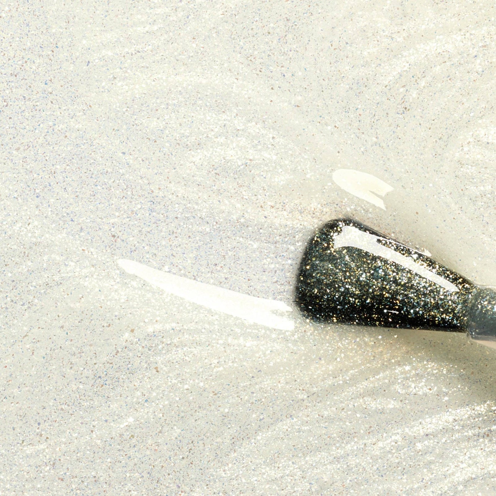 Close-up of a gold glittery top coat swatch