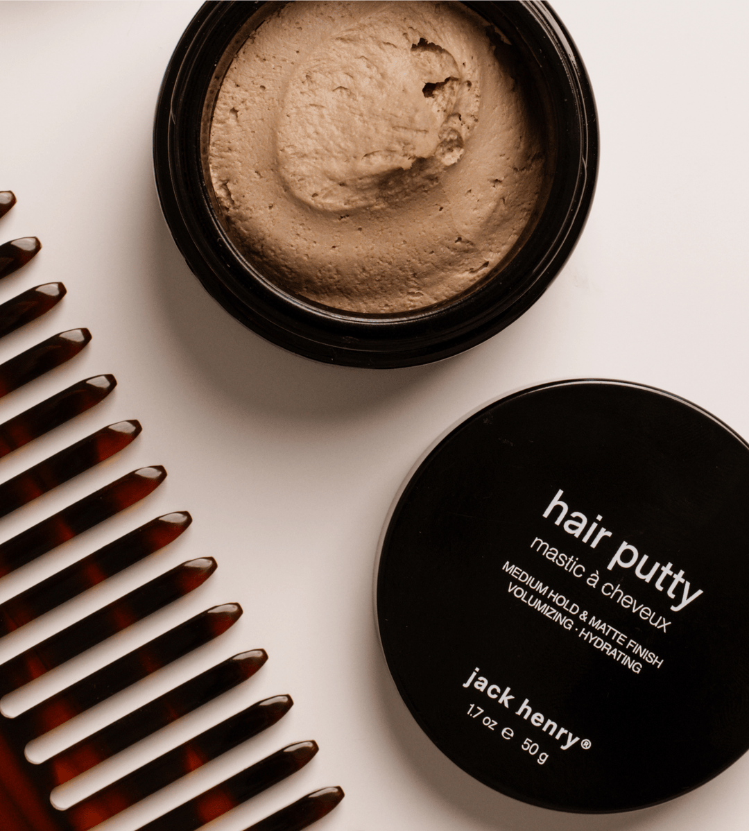 Jar of hair putty with comb on a light background
