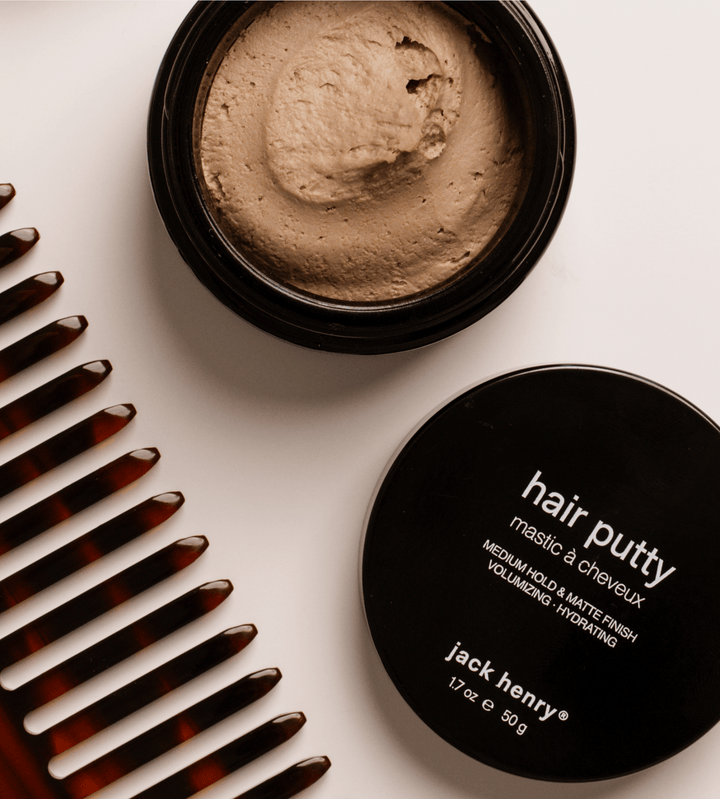 Jar of hair putty with comb on a light background