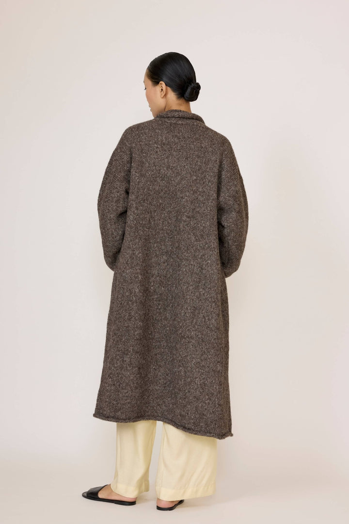 Person wearing a Laude Heirloom Sweater Coat in Nutty Brown over a light yellow shirt and pants on a white background