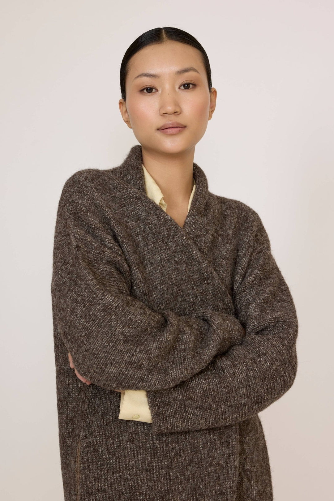 Person wearing a Laude Heirloom Sweater Coat in Nutty Brown over a light yellow shirt on a white background