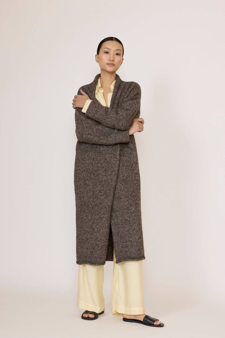 Person wearing a Laude Heirloom Sweater Coat in Nutty Brown over a light yellow shirt and pants on a white background