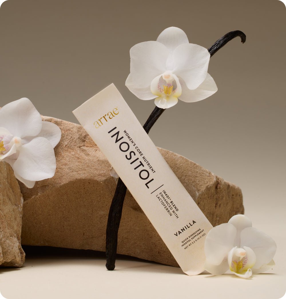 INOSITOL supplement with vanilla bean and orchids on a neutral background