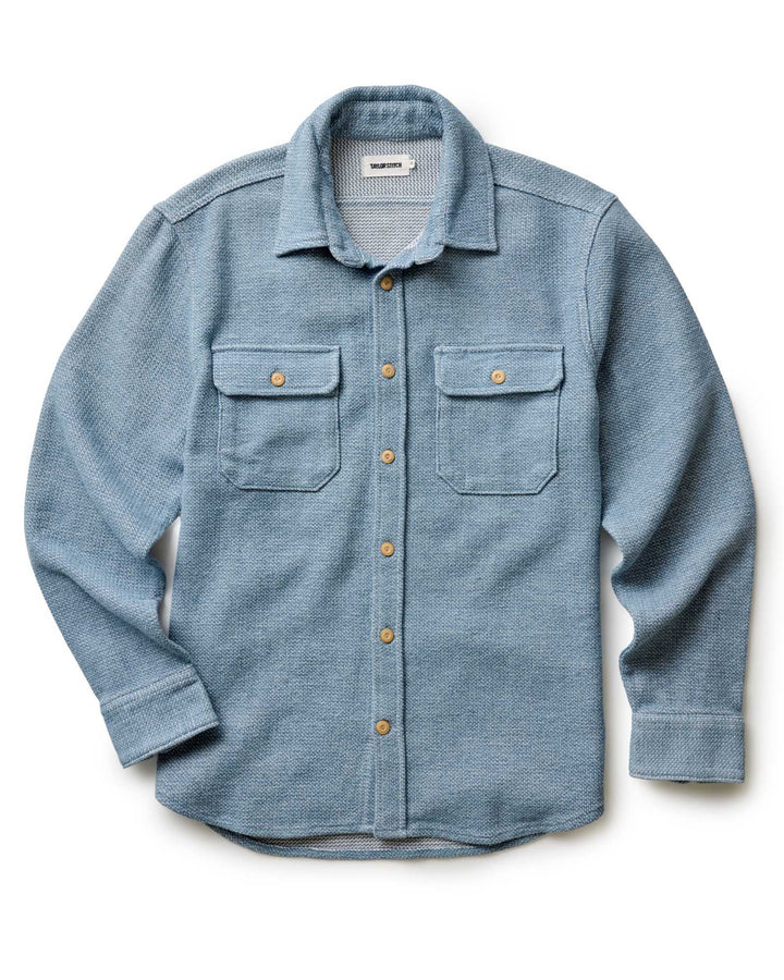 Blue flannel shirt with button details on a white background