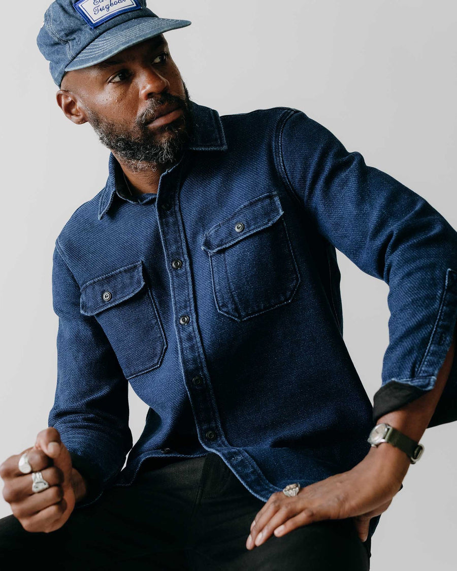 Man wearing a blue denim shirt and cap against a plain background