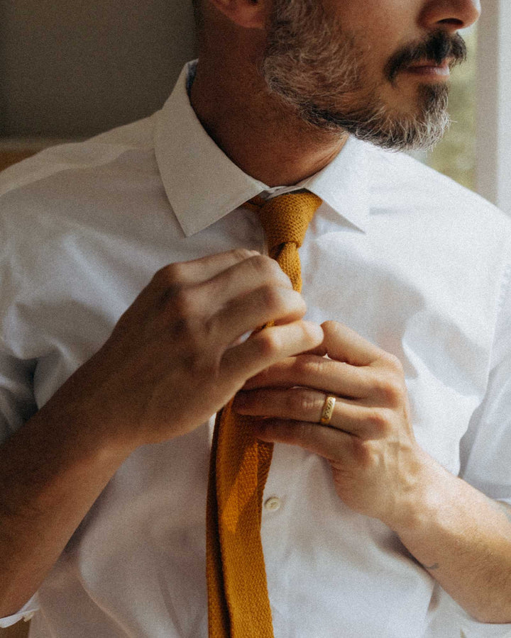 close-up white dress shirt with man putting on tie.