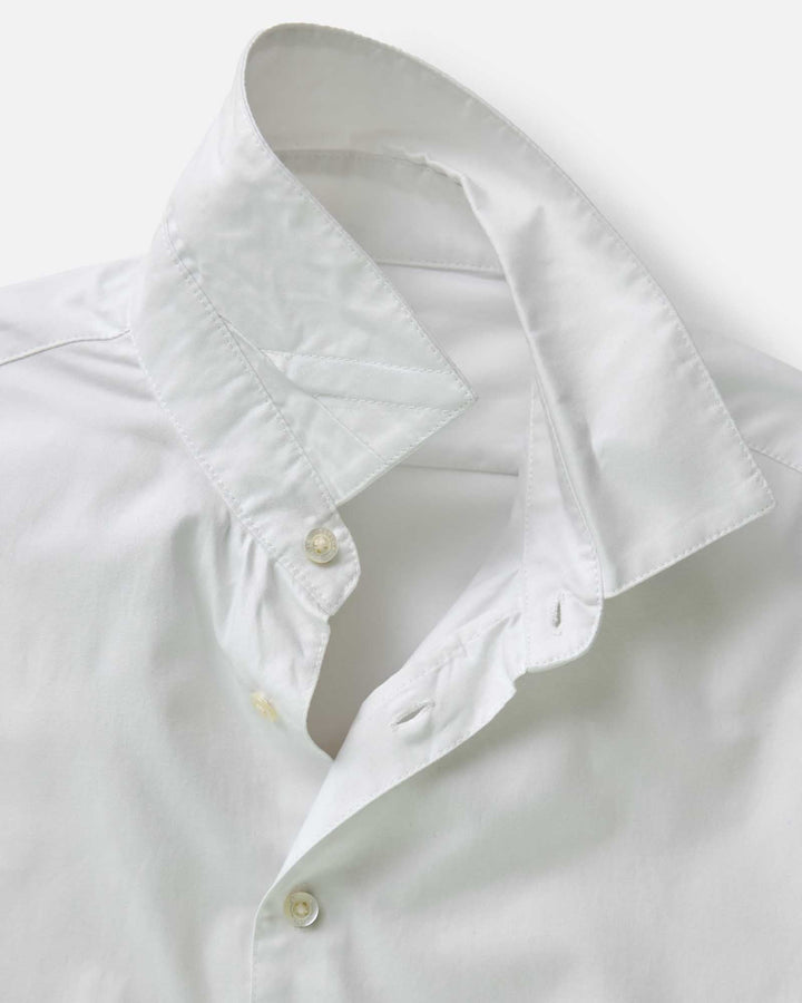 Close-up of a white shirt with a collar and buttons on a light gray background