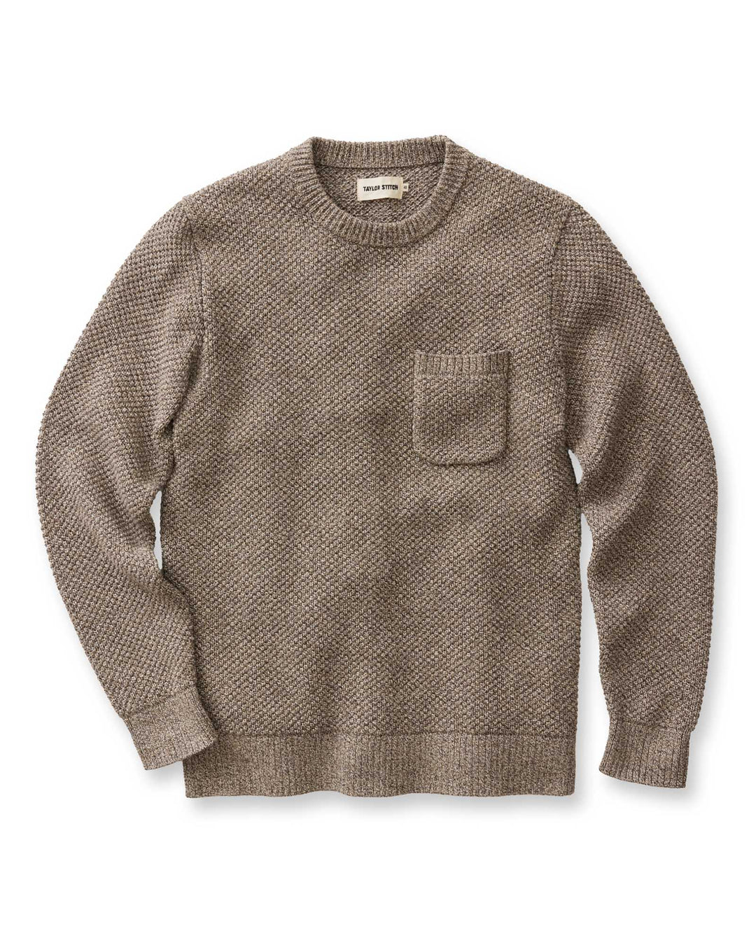A man wearing Crawford Crew Sweater in Coffee Twist with a chest pocket, against a white backdrop.