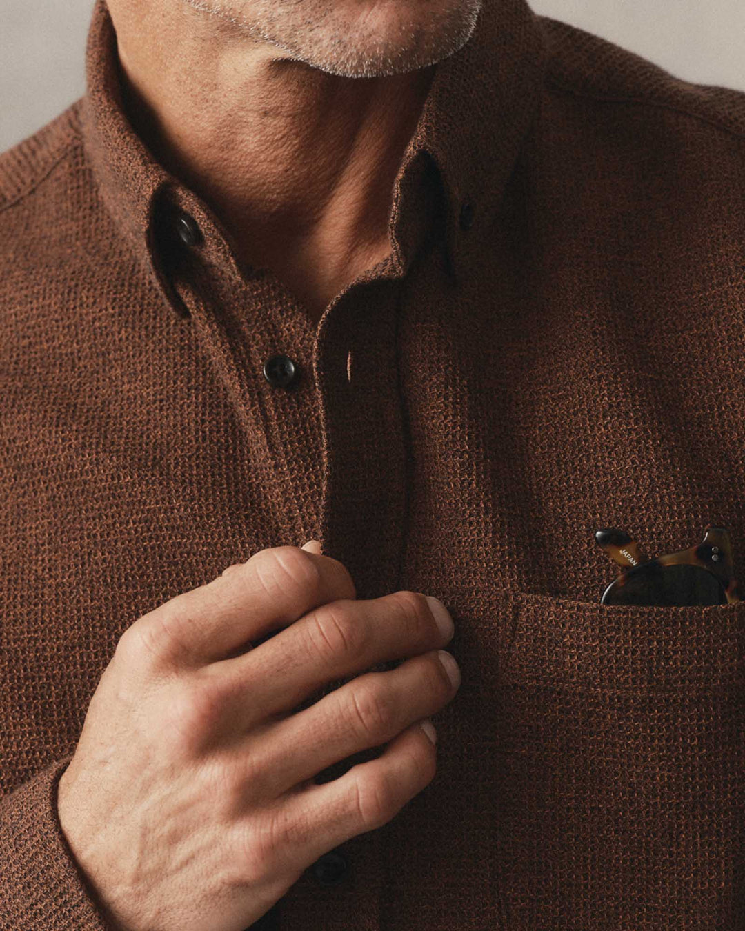 Close-up of a man wearing The Jack Shirt in Timber Twist Waffle, adjusting the collar with one hand while resting the other on a chest pocket.