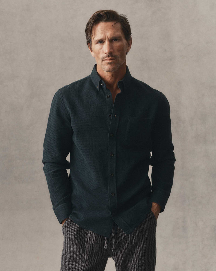 A man wearing The Jack in Forest Waffle and textured gray pants, standing against a neutral textured gray background.