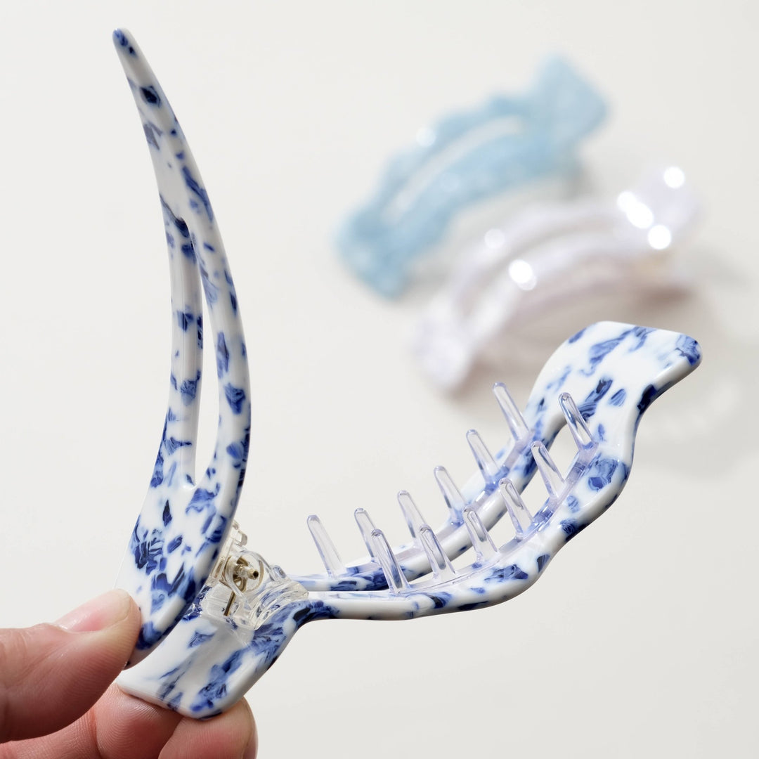 Coastal blue hair clip held by a hand on a light background