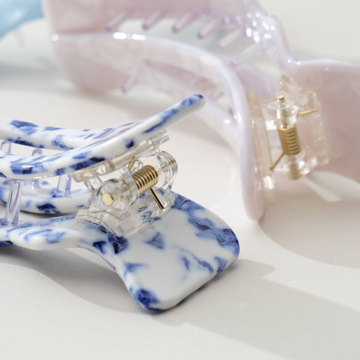 Two Adorro hair clips in Coastal blue and Ivory on a light background 