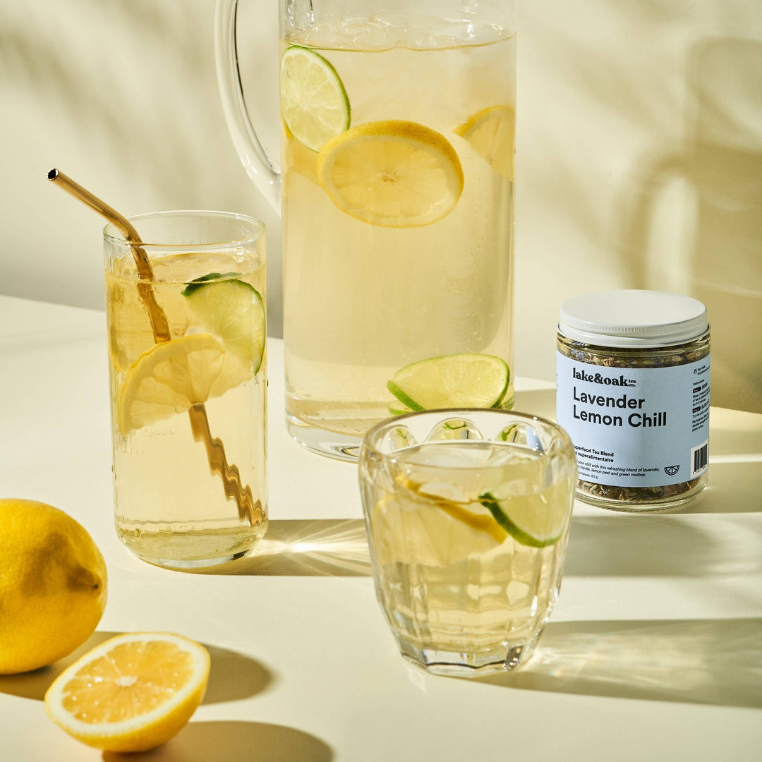 Clear pitcher and glasses of lemonade with lemon slices and a jar labeled &