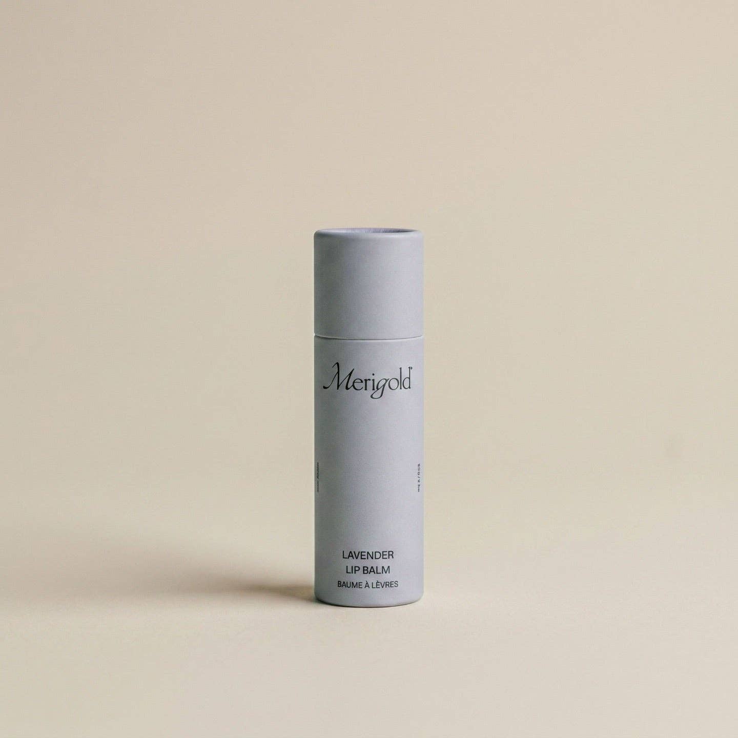 Lavender lip balm in a light purple cylindrical container on a beige background