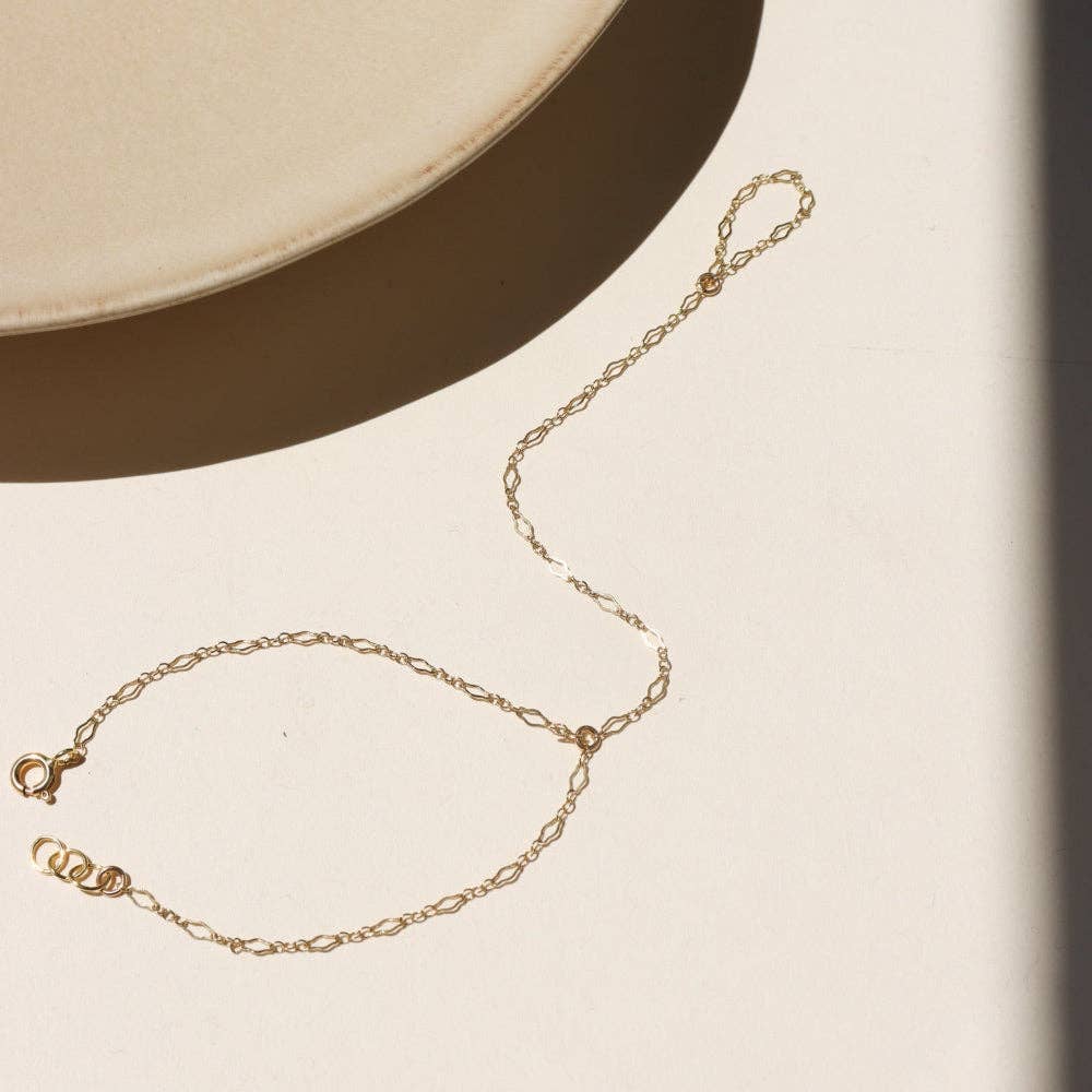 Gold hand chain on a beige surface with a neutral background