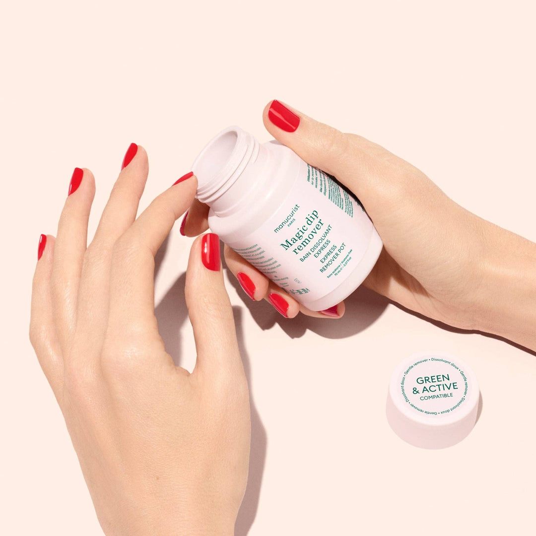 Hand holding a magic dip remover container with green text on a light pink background