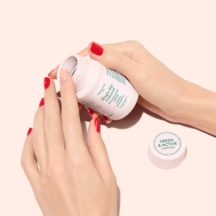 Hand holding a magic dip remover container with green text on a light pink background