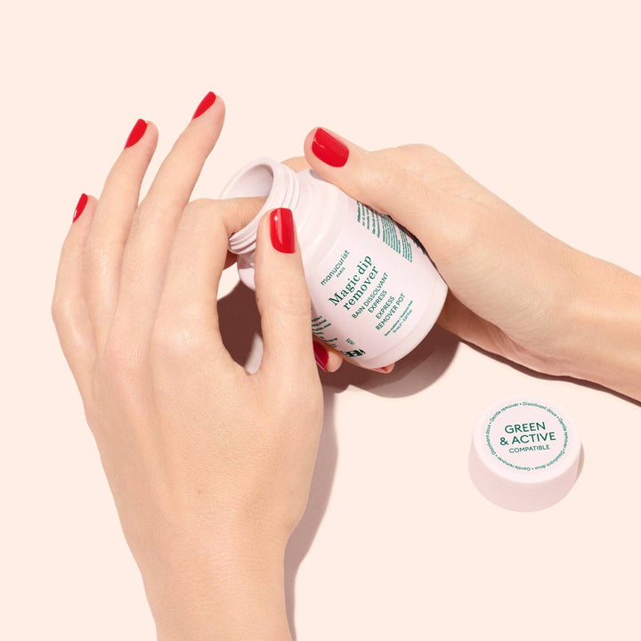 Hand holding a magic dip remover container with green text on a light pink background