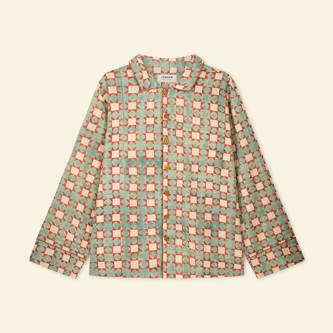 A long-sleeve button-up shirt by Yonder featuring a repeating geometric pattern in sage green, terracotta orange, and cream, laid flat against a light cream background.