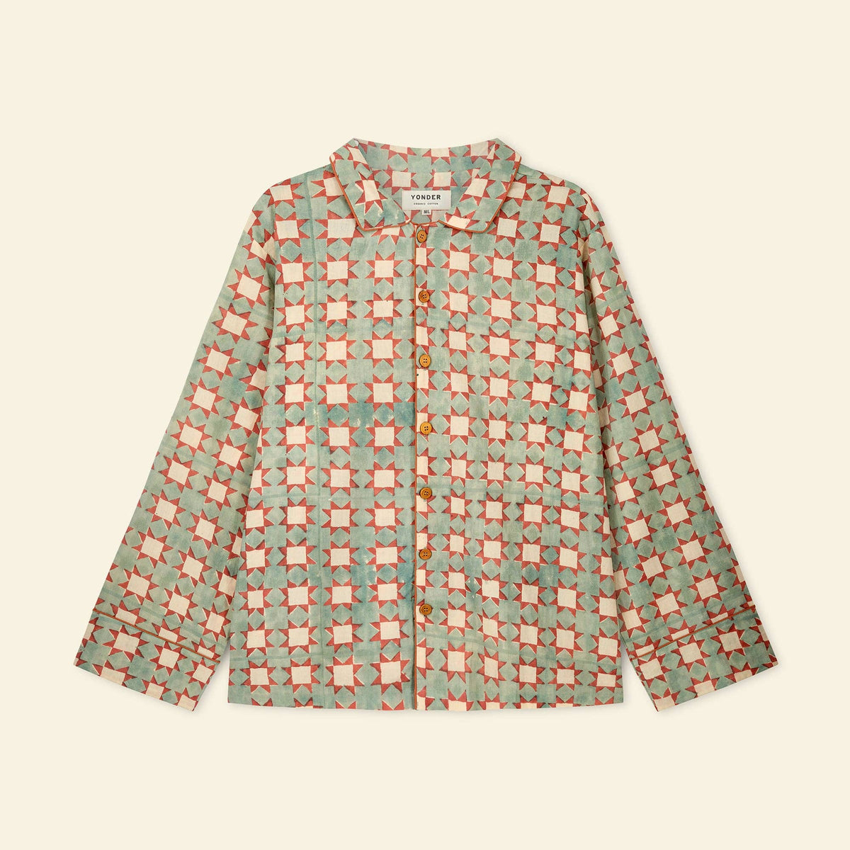 A long-sleeve button-up shirt by Yonder featuring a repeating geometric pattern in sage green, terracotta orange, and cream, laid flat against a light cream background.