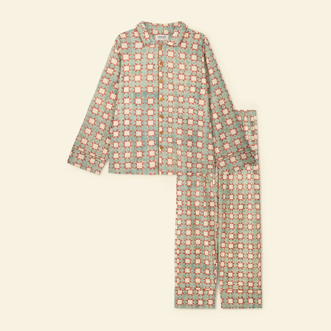 A two-piece yonder pajama set ffor men, eaturing a long-sleeve button-up shirt and matching pants in a muted sage green color with a repeating coral and peach geometric grid pattern, laid flat on a light cream background.