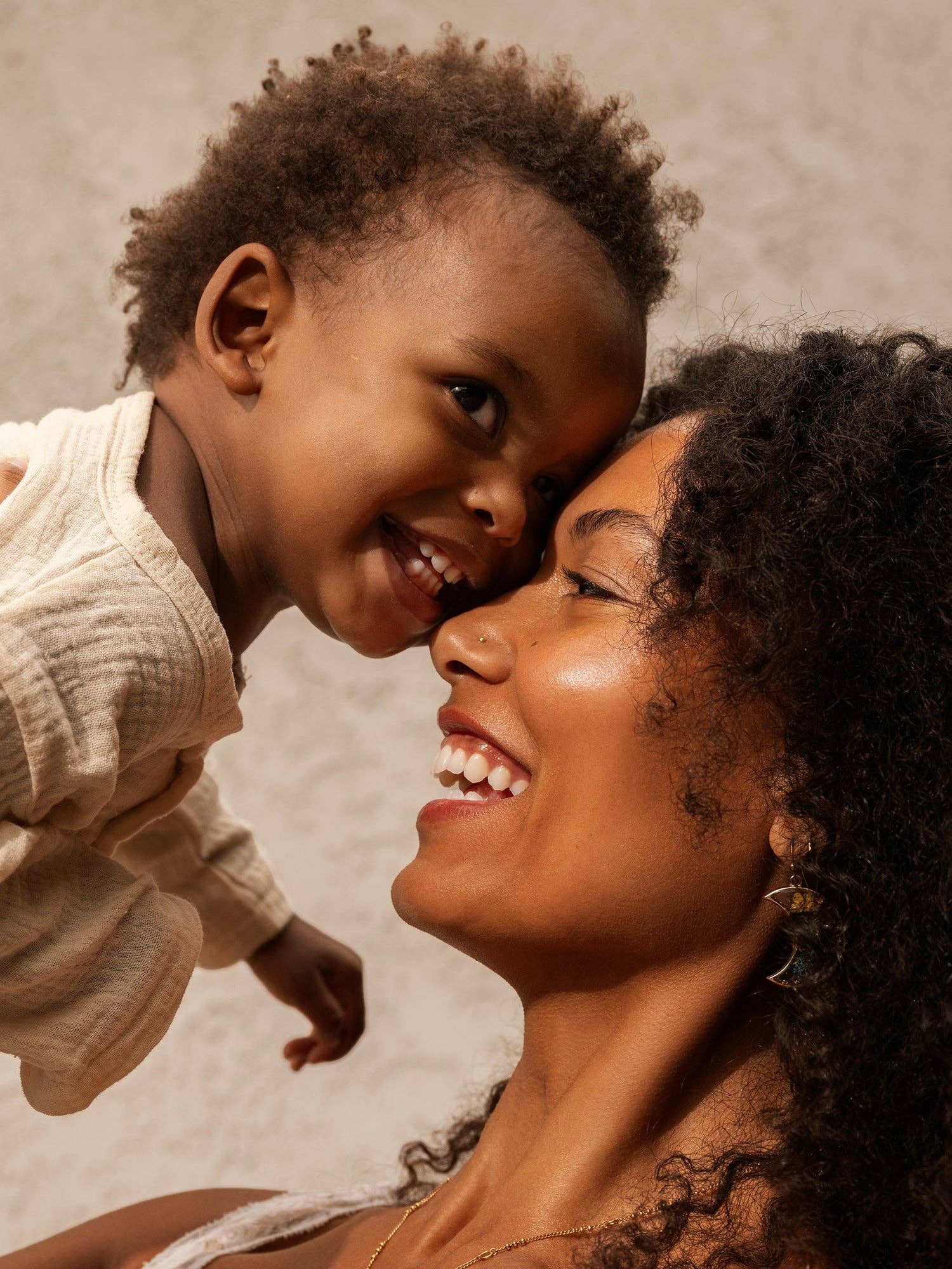 Woman and child smiling at each other against a neutral background
