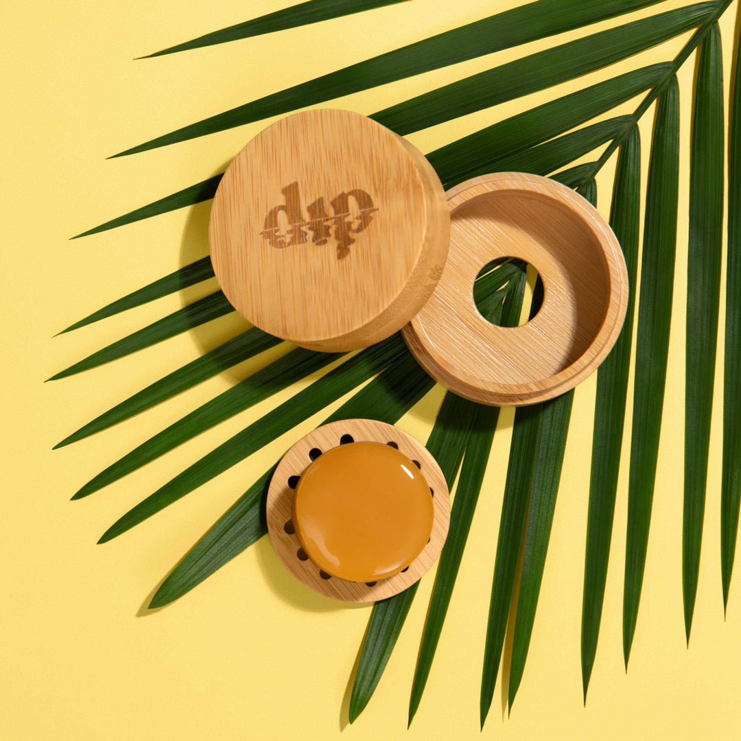 Mini Dip Bamboo Travel Case with Coaster on a yellow background with palm leaves.
