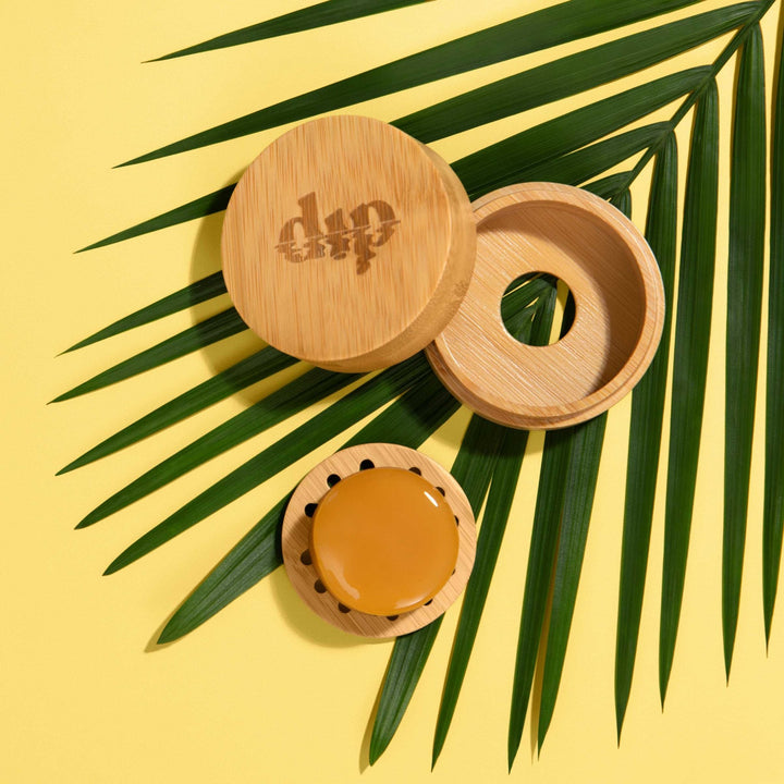 Mini Dip Bamboo Travel Case with Coaster on a yellow background with palm leaves.