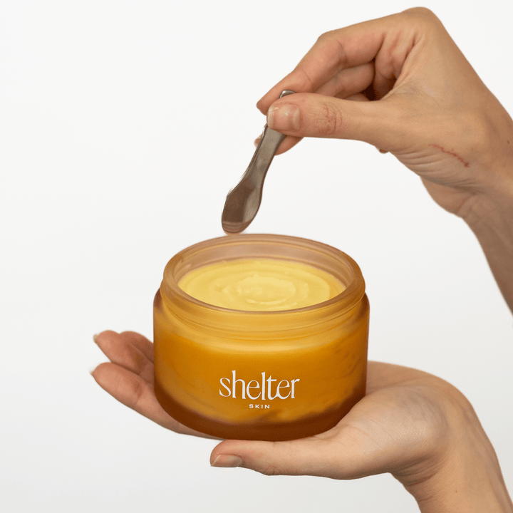 Hand holding a jar of No. 1 Solar Tallow Body Butter with a product spoon.