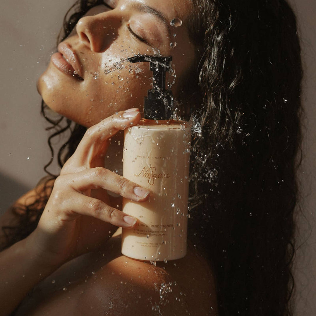 Woman holding a bottle of Najeau with water splashing around, against a neutral background