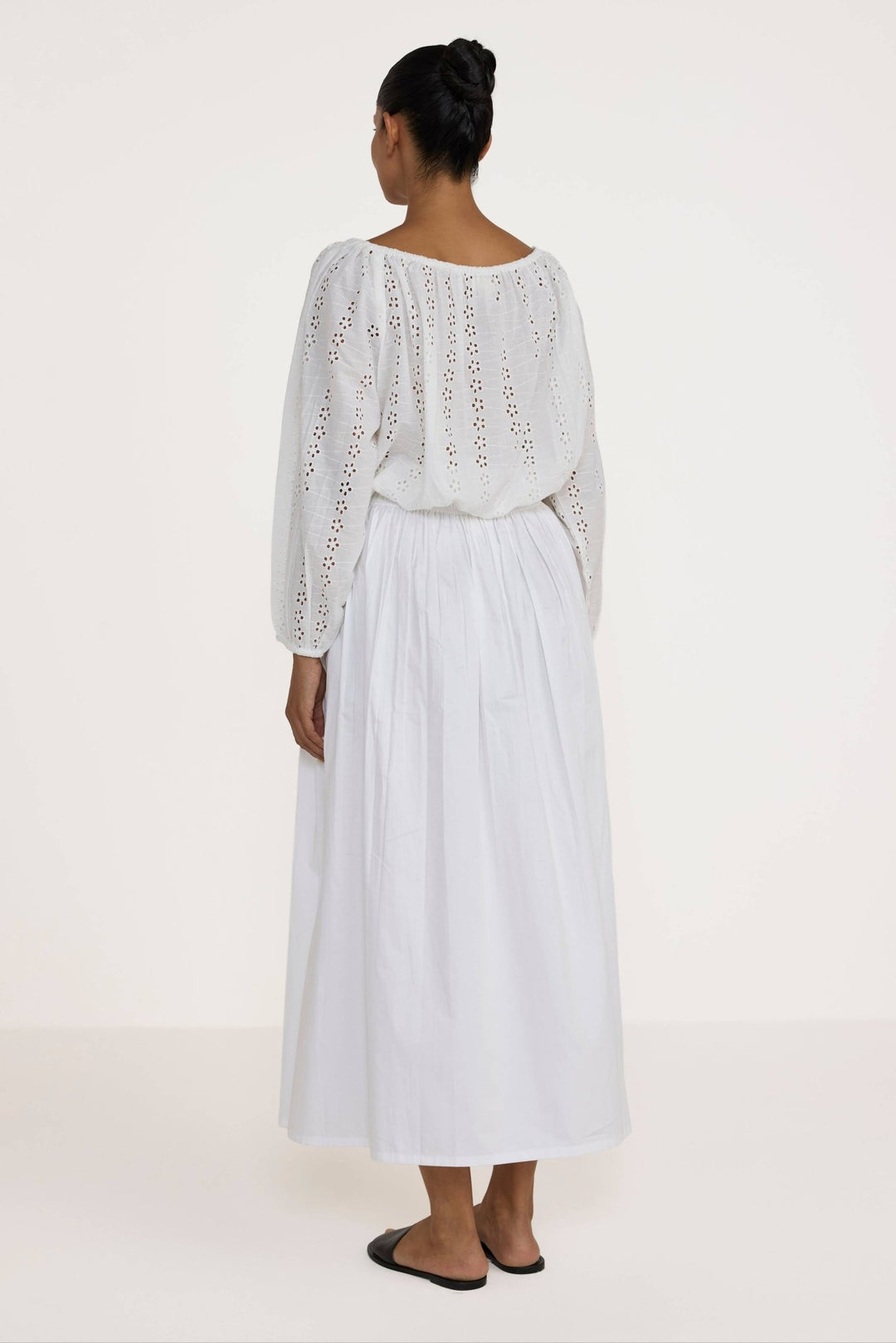 Woman wearing a Laude the Label Off The Shoulder Blouse in Ivory Lace with intricate detailing on a plain background