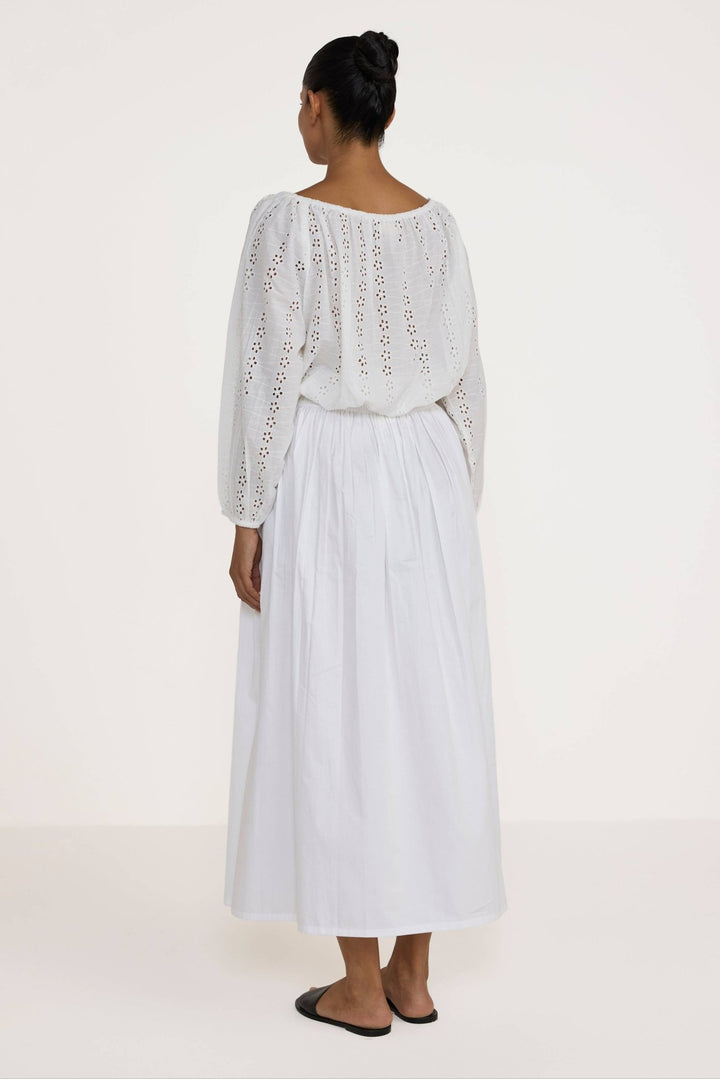 Woman wearing a Laude the Label Off The Shoulder Blouse in Ivory Lace with intricate detailing on a plain background