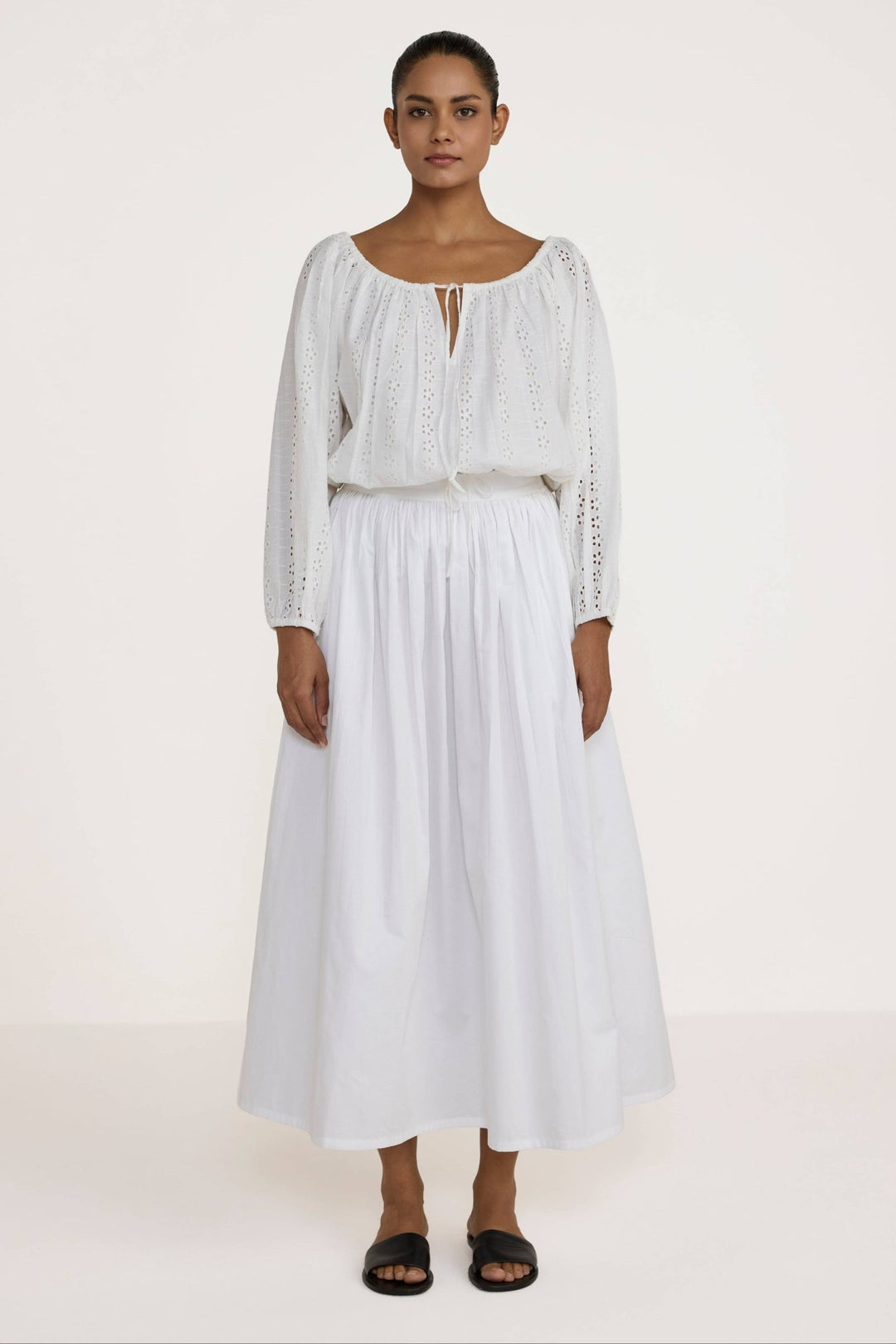 Woman wearing a Laude the Label Off The Shoulder Blouse in Ivory Lace with intricate detailing on a plain background