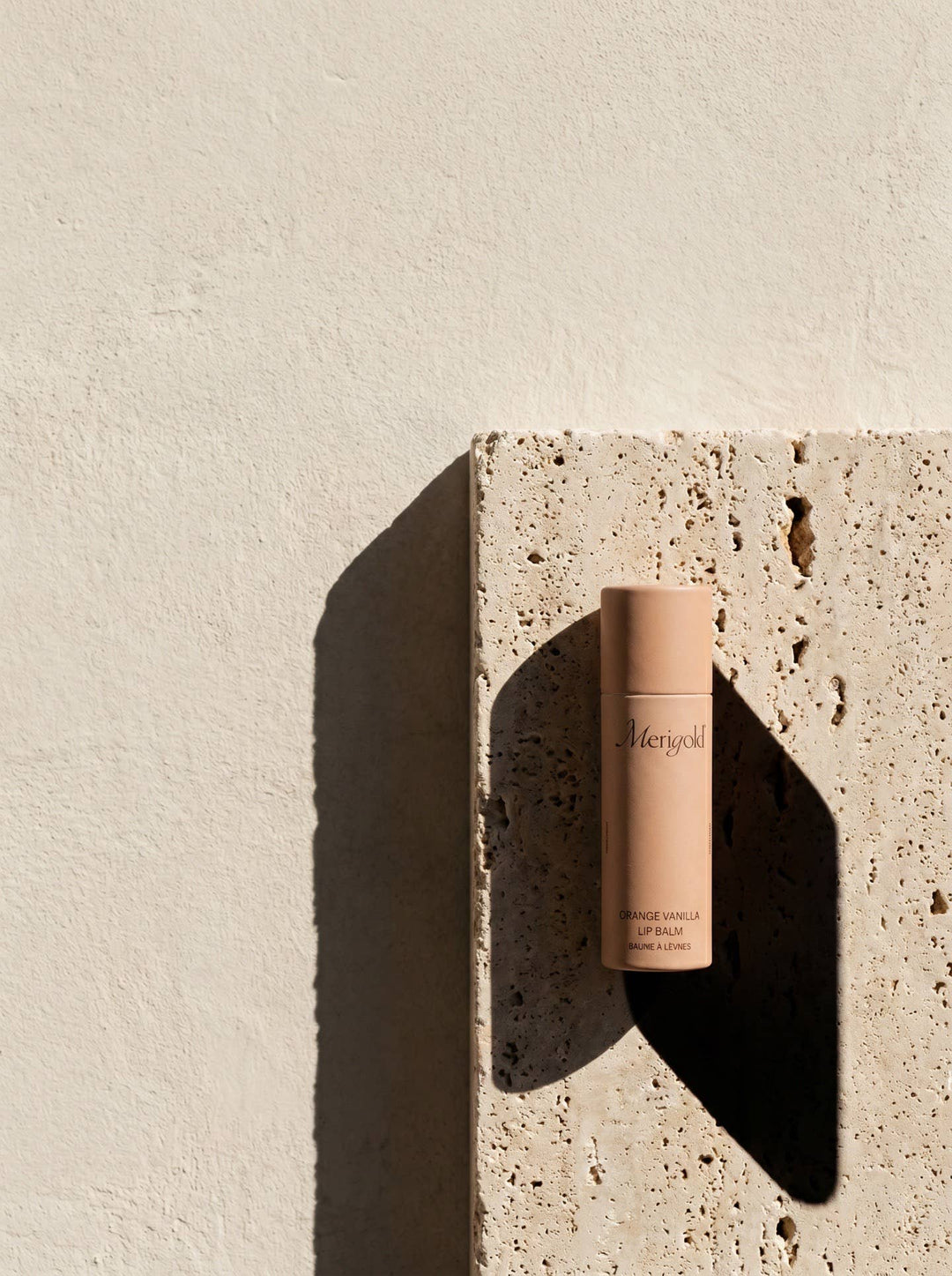 Lip balm on a textured stone surface with a neutral background