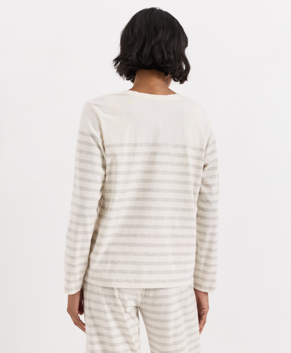A person shown from the back wearing a long-sleeve striped top and matching striped pants in a light cream and beige colorway, against a plain white studio background.