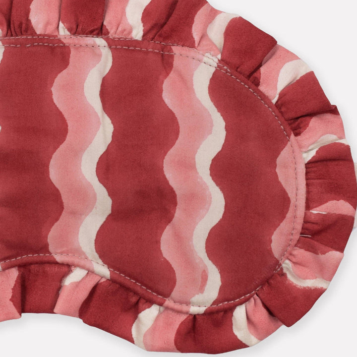 Close-up of a red and pink patterned eye mask on a white background