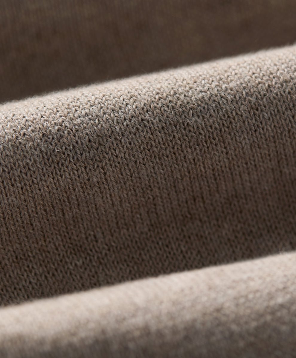 Close-up of a soft knit fabric with a fine ribbed texture in soft umber heather, draped in layered folds.