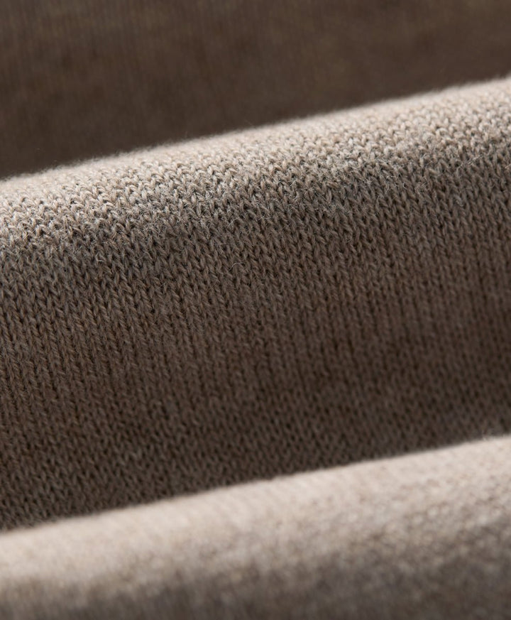 Close-up of a soft knit fabric with a fine ribbed texture in soft umber heather, draped in layered folds.