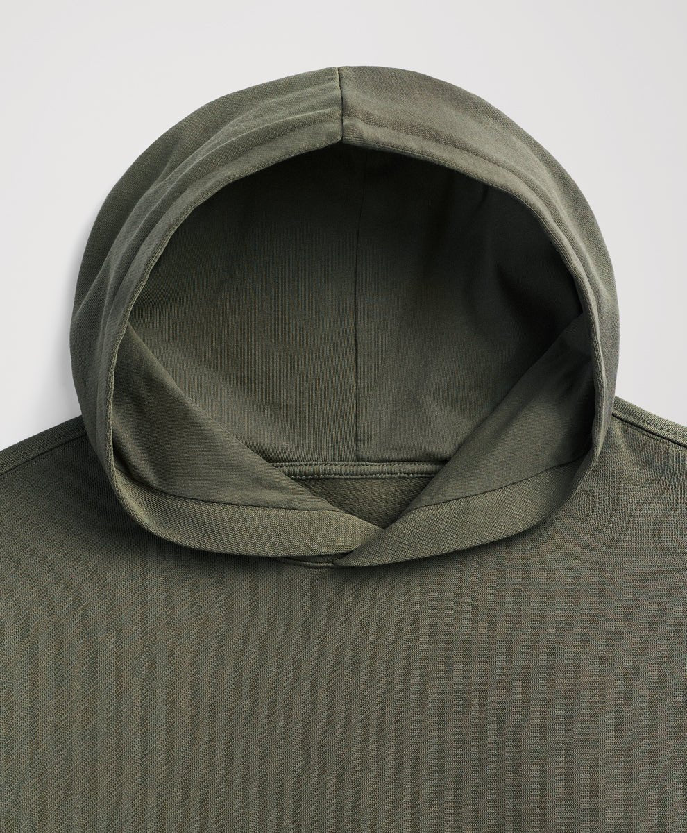 Close-up of the hood and upper chest of a dusted green hoodie against a light gray background.