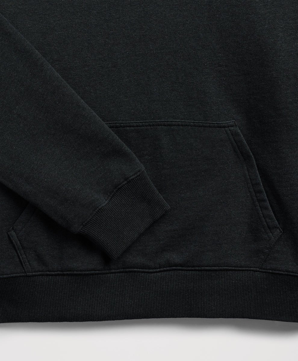 Close-up of a charcoal heather sweatshirt showing the sleeve cuff, ribbed hem, and a front kangaroo pocket.