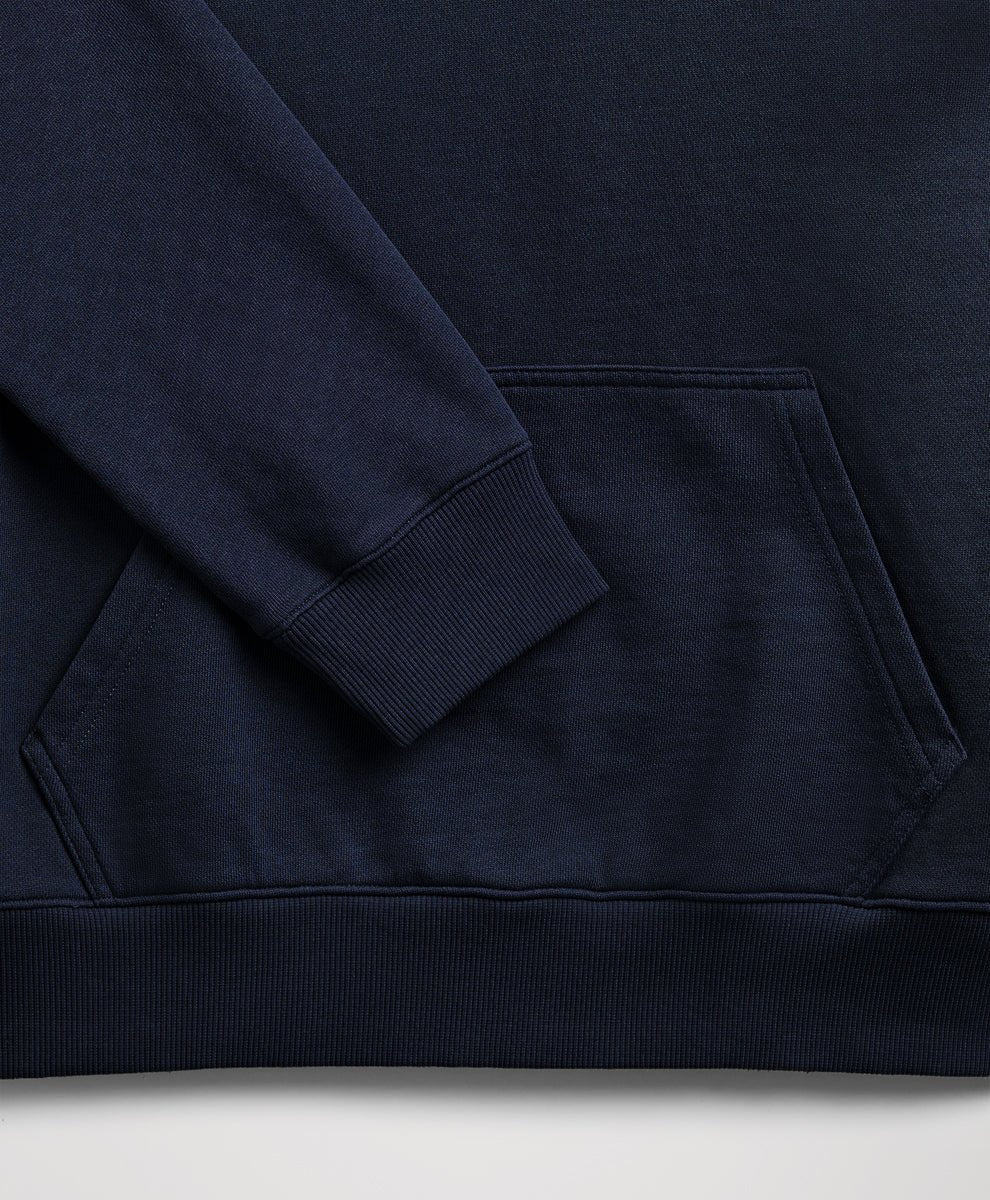 Close-up of a dark navy blue sweatshirt showing the sleeve cuff, ribbed hem, and front kangaroo pocket.