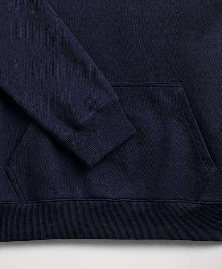 Close-up of a dark navy blue sweatshirt showing the sleeve cuff, ribbed hem, and front kangaroo pocket.