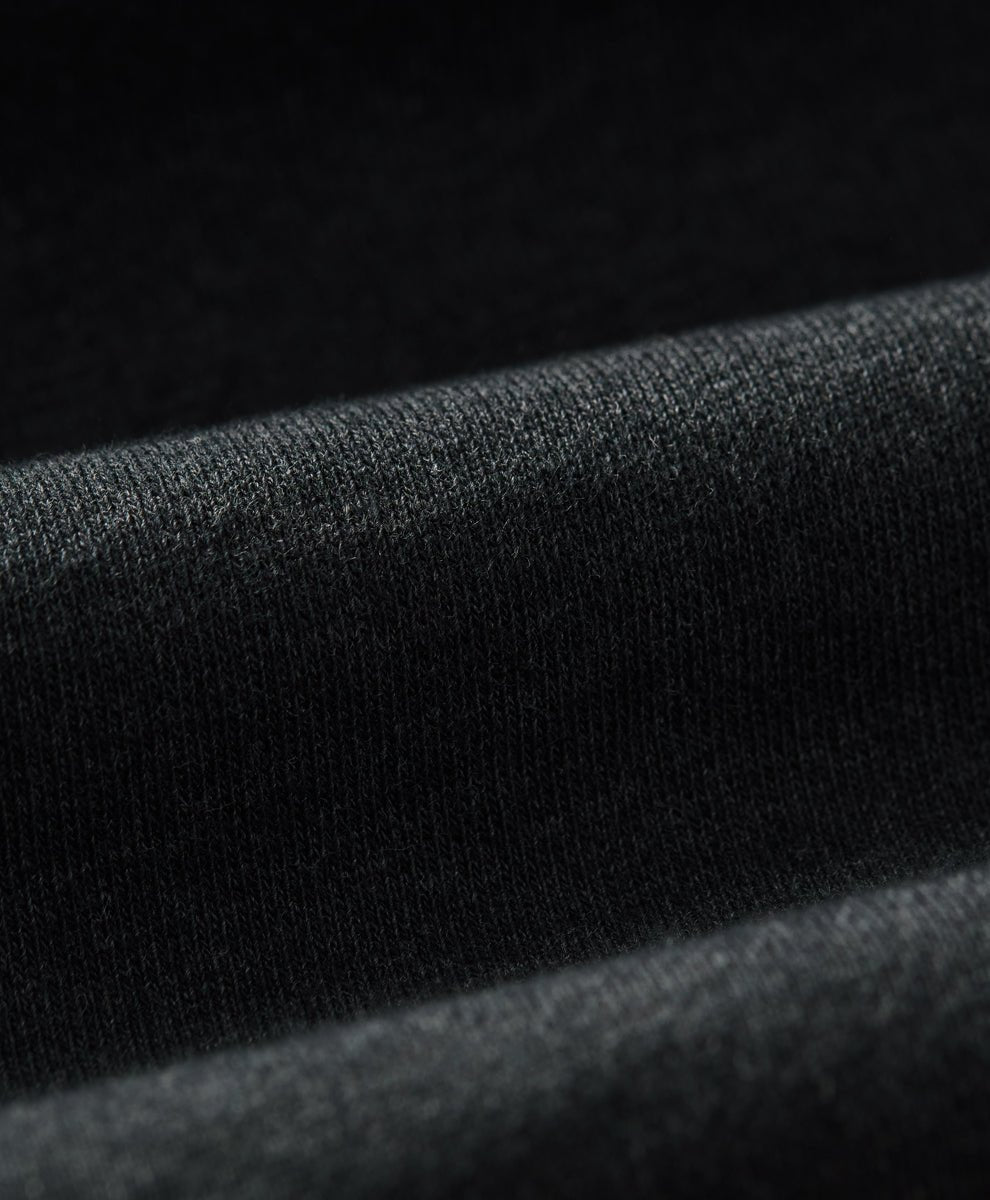Close-up of a charcoal heather knit fabric with soft folds and a fine textured weave.