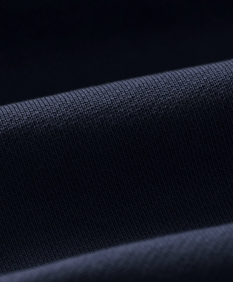 Close-up of dark navy blue knit fabric with a fine ribbed texture and soft folds.