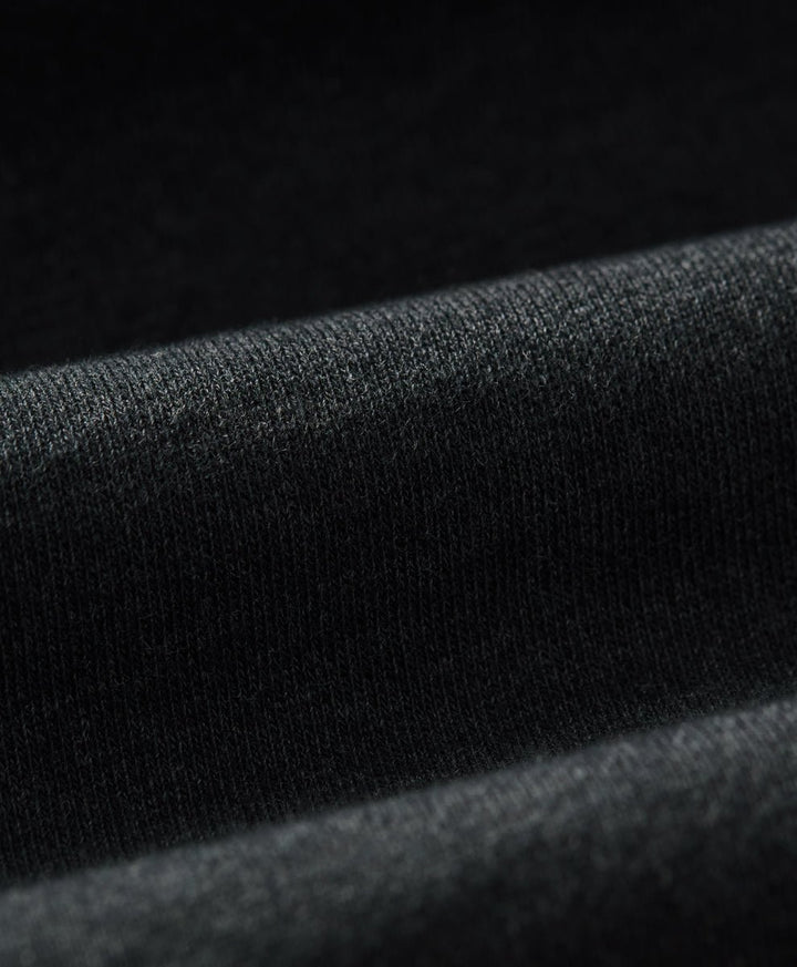 Close-up of a charcoal heather knit fabric with soft folds and a fine textured weave.