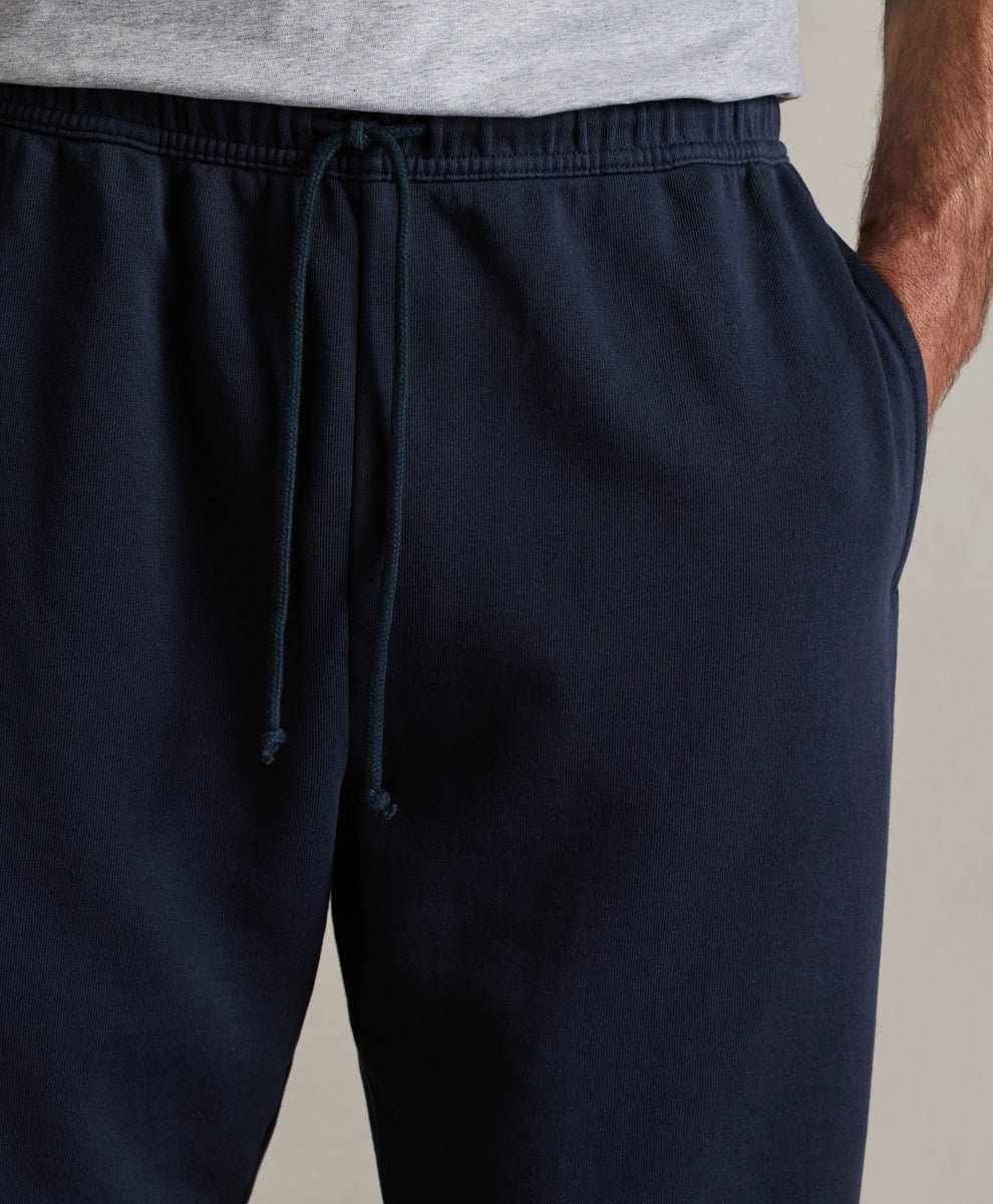 Close-up of a person wearing dark navy drawstring sweatpants with a light gray shirt partially visible at the waist.