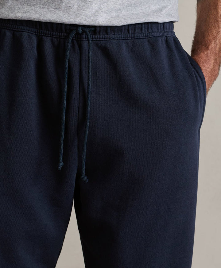 Close-up of a person wearing dark navy drawstring sweatpants with a light gray shirt partially visible at the waist.