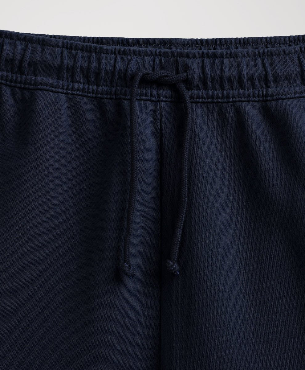 Close-up of navy blue sweatpants showing the elastic waistband and matching drawstring.
