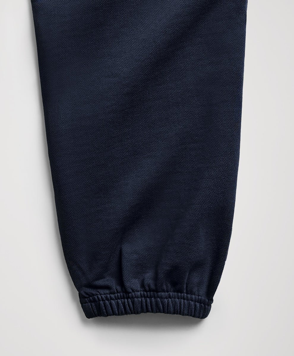Close-up of a dark navy blue fabric pant leg with an elasticized cuff, shown against a light gray background.