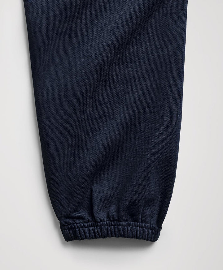 Close-up of a dark navy blue fabric pant leg with an elasticized cuff, shown against a light gray background.